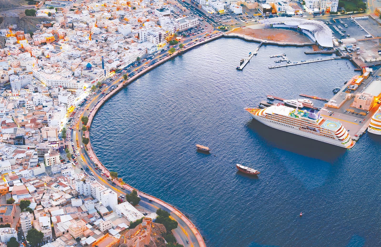 Aerial view at dusk of Muttrah harbour and corniche, Muscat, Oman.